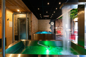 Bain froid en inox dans l'espace wellness d'un établissement, avec douche cascade et éclairage d'ambiance