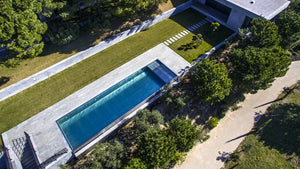 Piscine en inox à débordement vue du ciel, ligne d'eau nette au milieu d'un jardin dans le Vaucluse