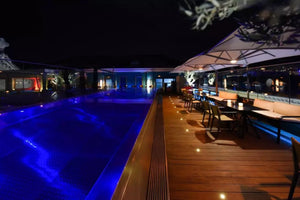 Piscine en inox de l'hôtel Five Seas à Cannes illuminée de nuit, en bordure de la terrasse et du bar