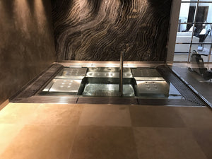 Spa en inox sur mesure encastré dans un sol en pierre, avec banquettes, buses et main courante