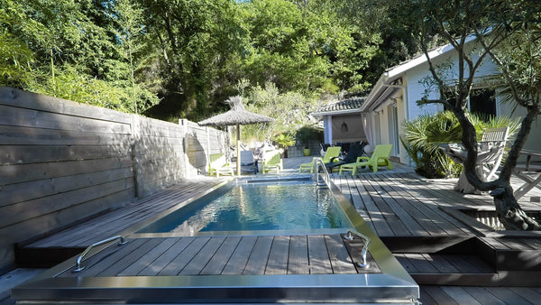 Piscine en inox avec plage en bois dans un jardin arboré, type de bassin réalisable en rénovation d'une piscine existante