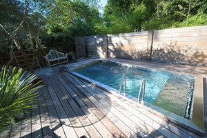 Piscine en inox avec échelle et plage en bois, dont la longueur oriente le choix d'une nage à contre-courant