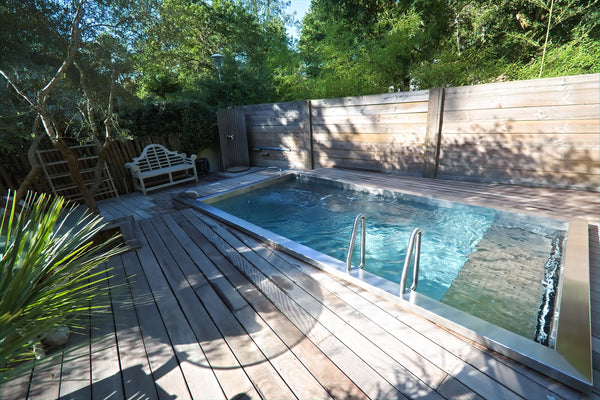 Piscine en inox avec échelle et plage en bois, dont la longueur oriente le choix d'une nage à contre-courant