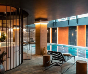 Piscine intérieure inox de l’hôtel Oceania Le Conti à Brest, transats et parois orangées