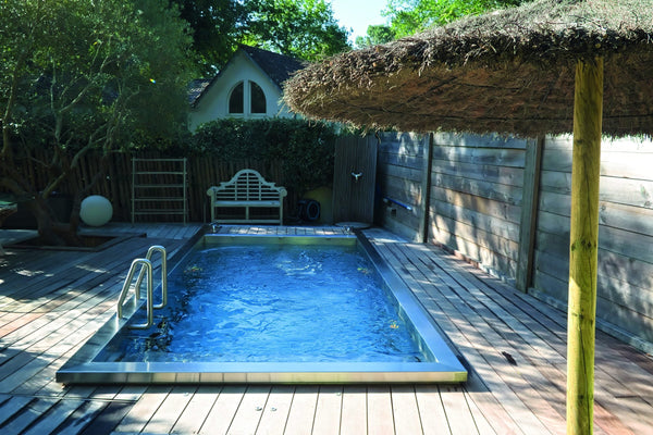 Spa de nage en inox encastré dans une terrasse en bois, parasol en paille