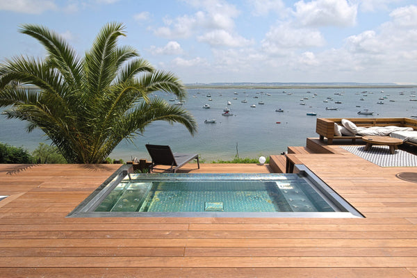 Spa inox à débordement encastré dans une terrasse en bois face au bassin d’Arcachon, au Cap Ferret